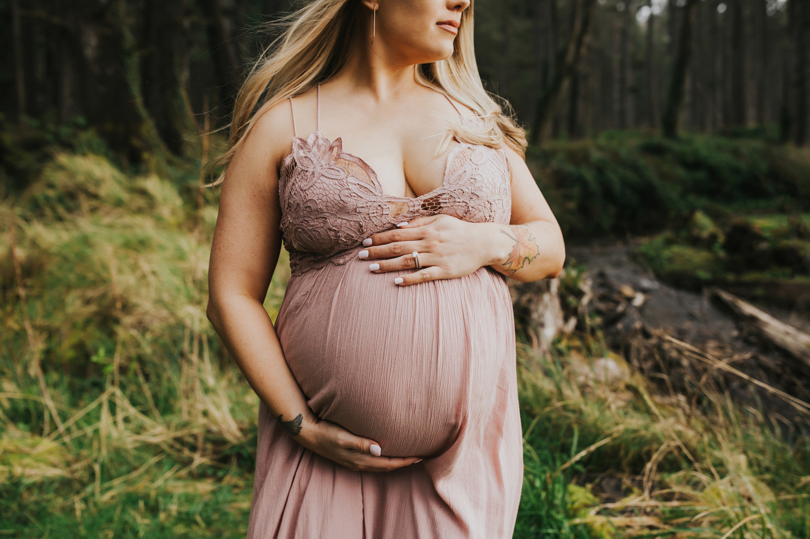 Close up on the bump of a pregnant woman in a pink dress during her maternity photo session on the Oregon Coast with Meg Ross Photography